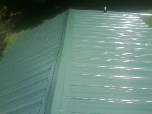 New green metal panels meeting at the ridge of a roof — Flat Roof Repair work by our crew in West Chazy