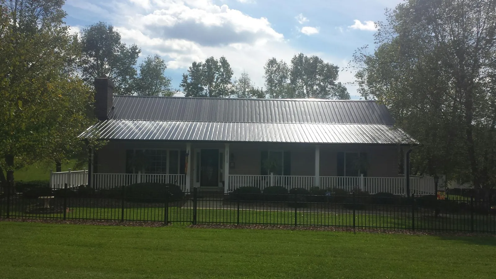 Gray metal roof on a brick ranch with a full width front porch — Gutter Guard Installation work by our crew in West Chazy