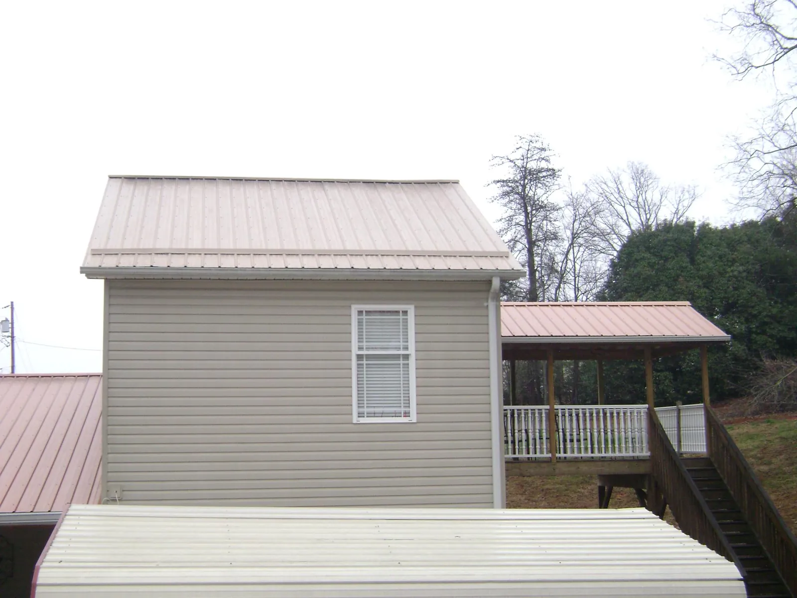 Tan metal roofs on a two story addition and attached porch, from a Roof Replacement job in West Chazy