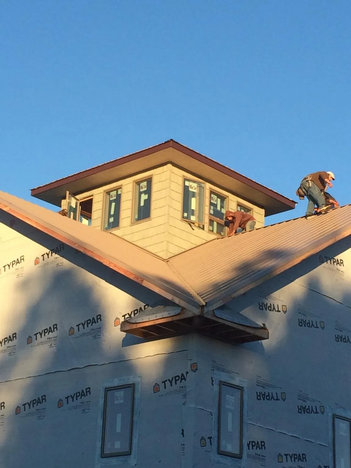 Roofers working around a rooftop cupola on a new metal roof at sunset — Roof Waterproofing in West Chazy by Roofing Brothers